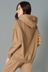 Woman wearing a brown hoodie and pants against a gray background