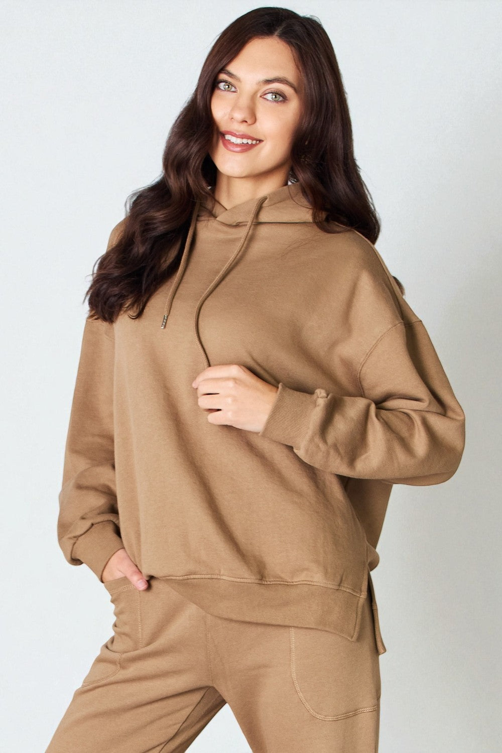 Woman wearing a brown hoodie and pants against a white background