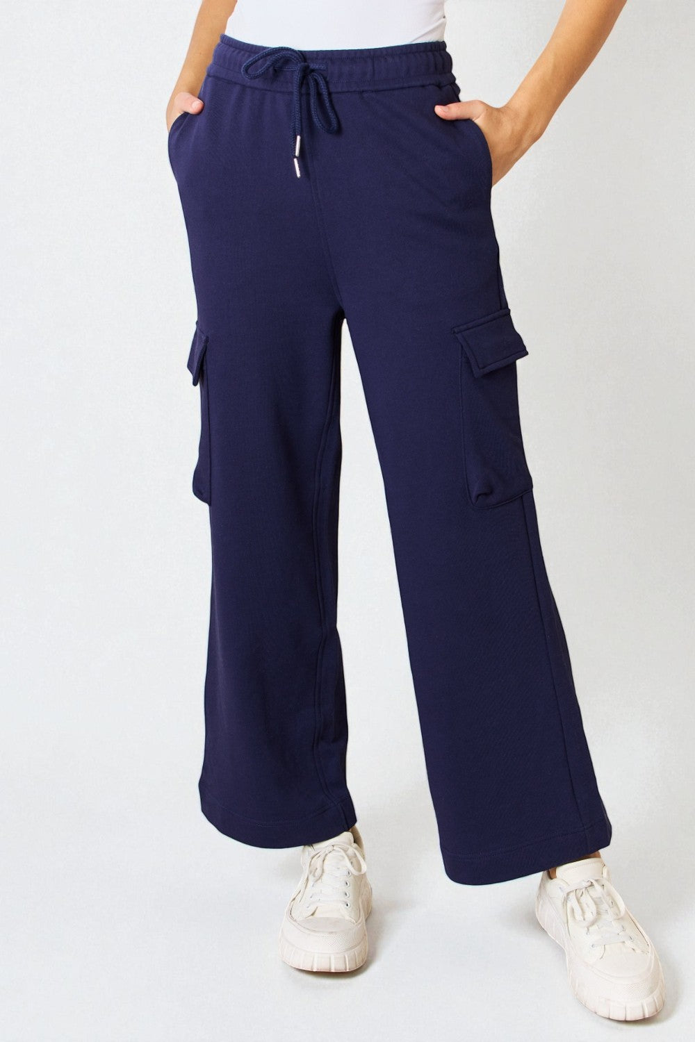 Navy cargo pants worn by a person on a white background