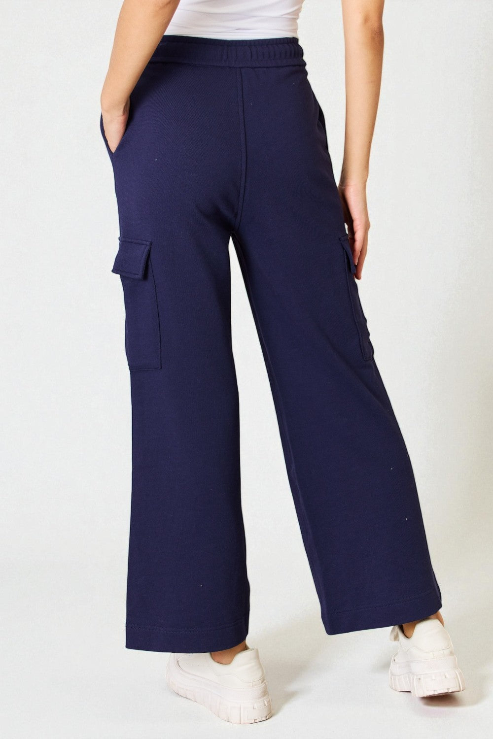 Navy cargo pants worn by a person on a white background