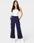 Woman wearing navy cargo pants and a white top on a light gray background