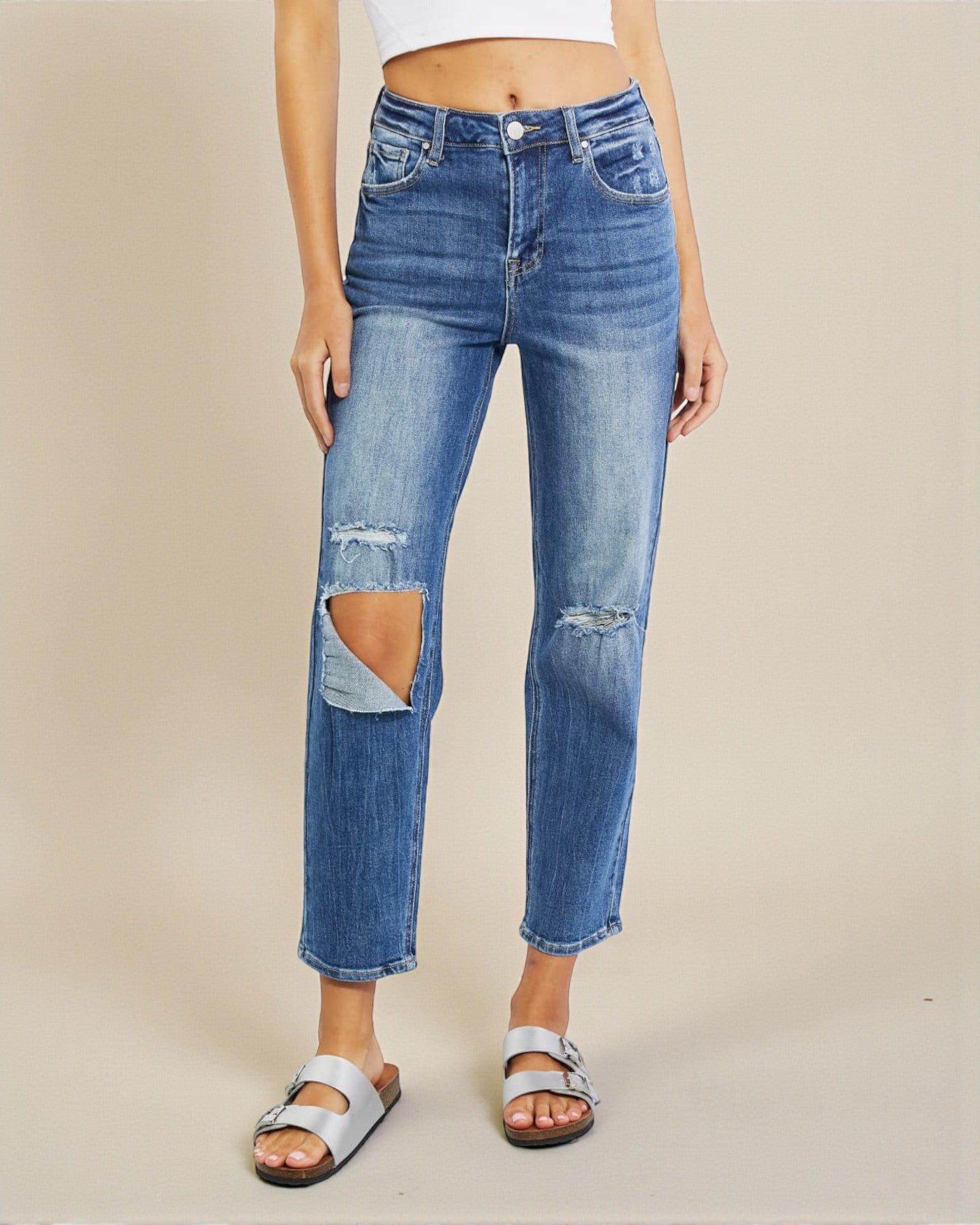 Person wearing blue ripped jeans on a beige background