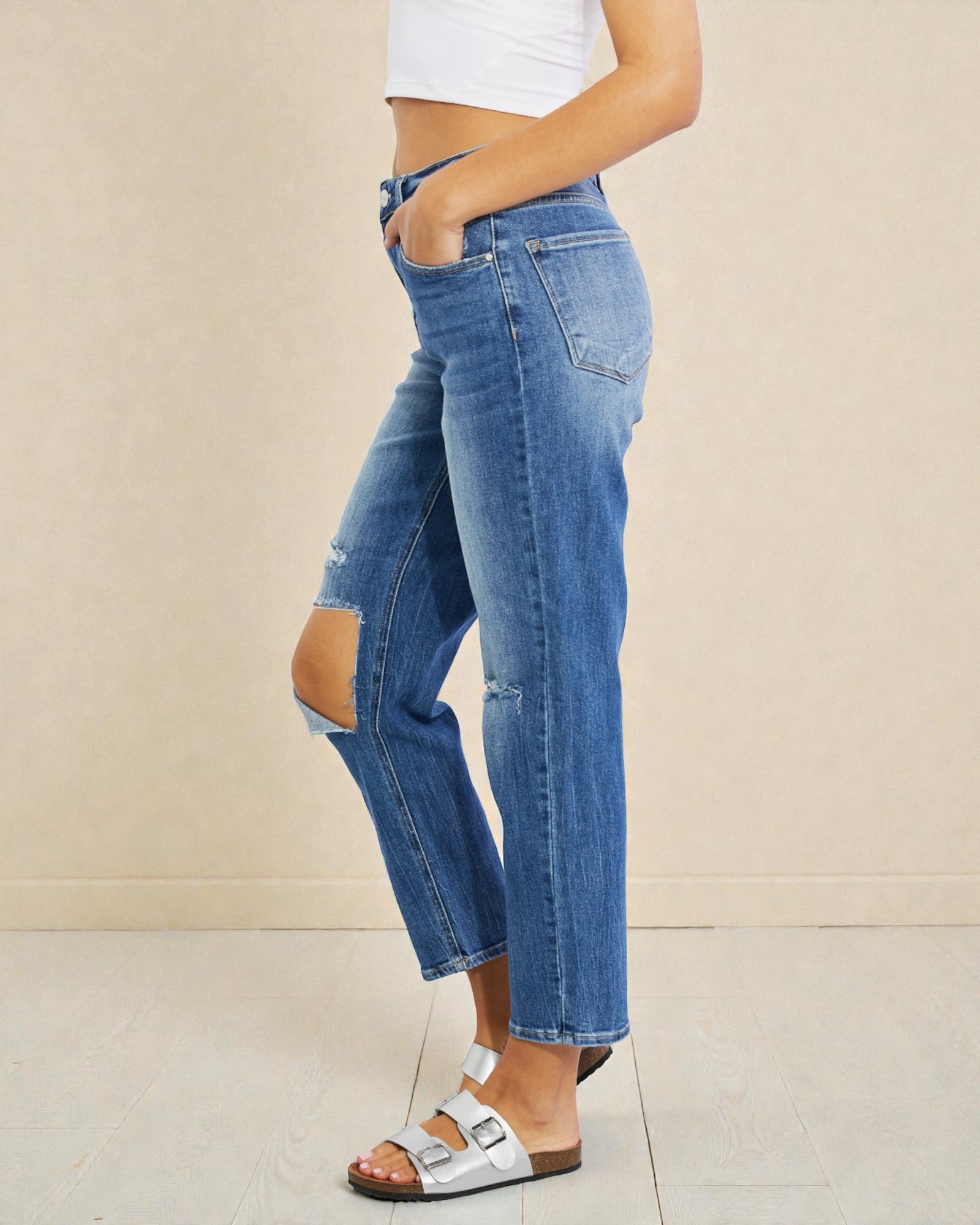 Person wearing blue jeans with a beige background