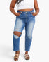 A model wearing high-waisted, distressed blue jeans with ripped knee patches, styled with a white crop top and metallic sandals against a light gray background.