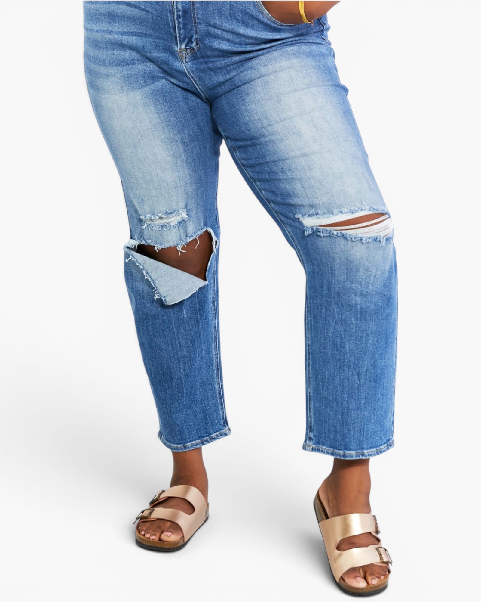 Light wash blue cropped jeans with distressed knee patches and frayed edges, shown on a model wearing metallic rose gold double-strap sandals against a plain white background.