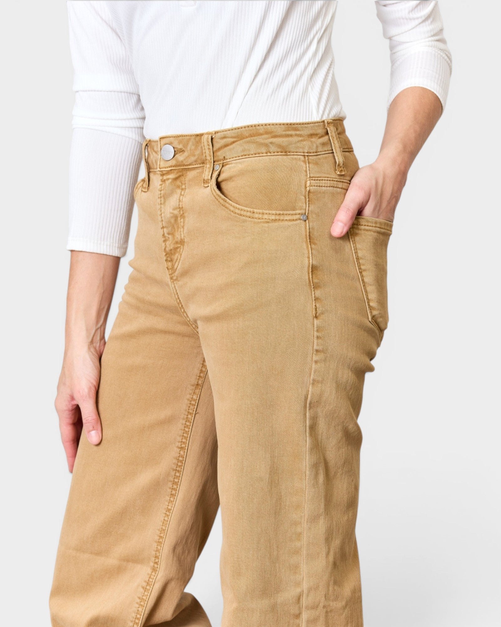 Person wearing tan pants with a white background
