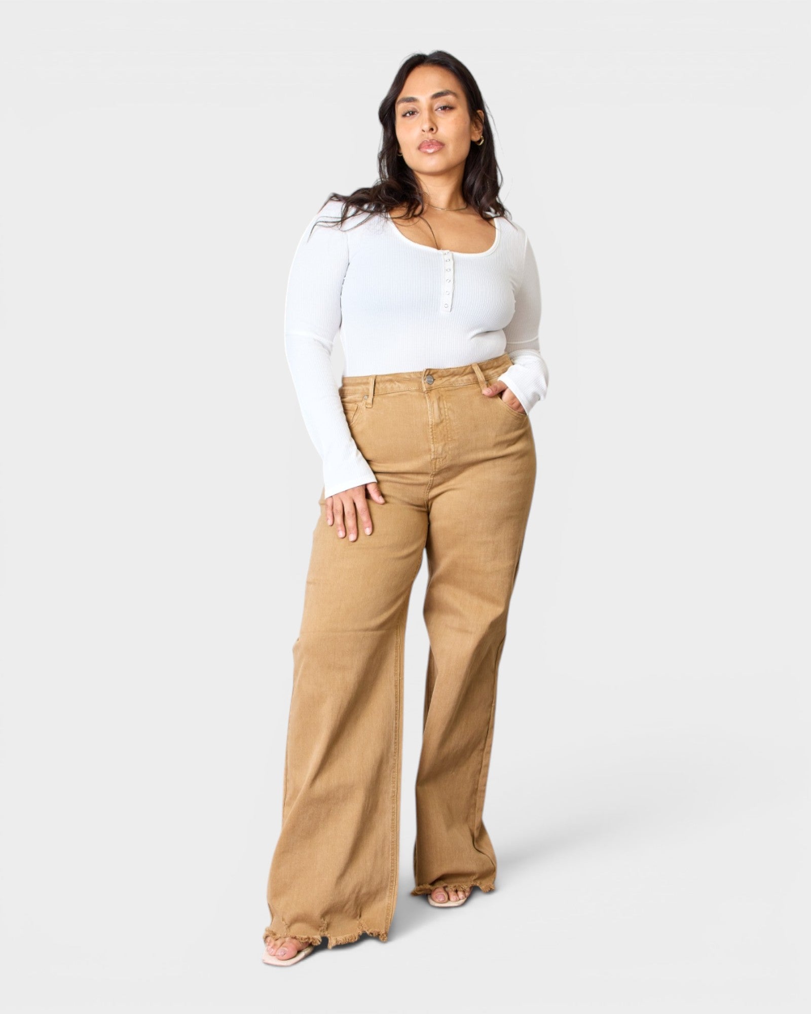 Woman wearing a white top and tan pants on a white background