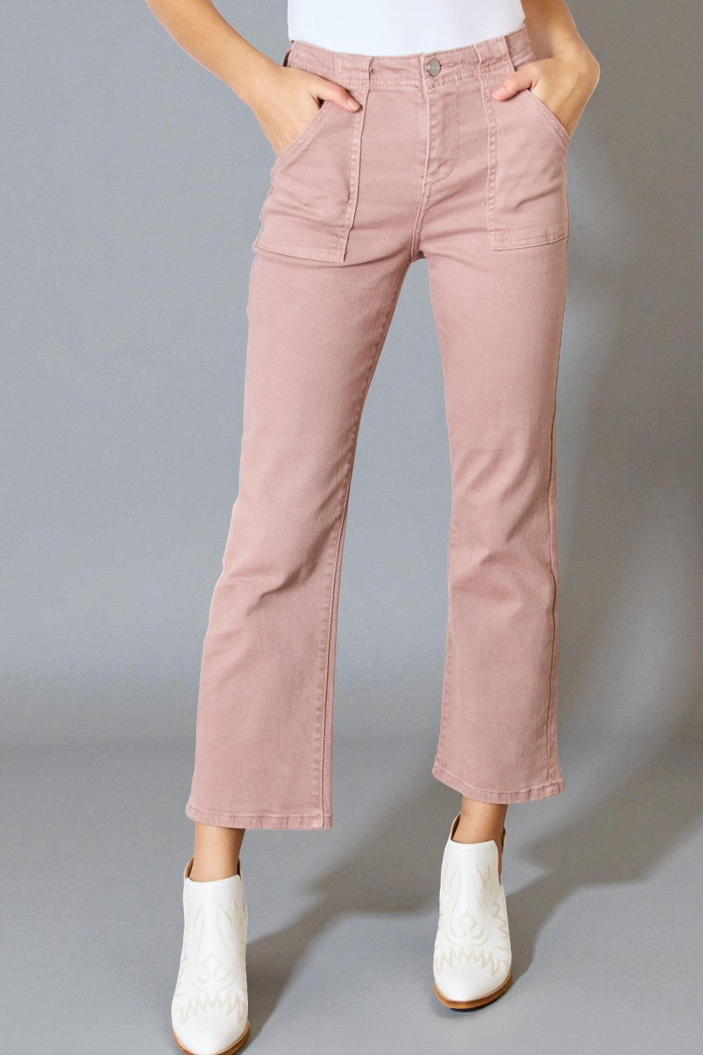 Person wearing pink pants with white shoes on a gray background
