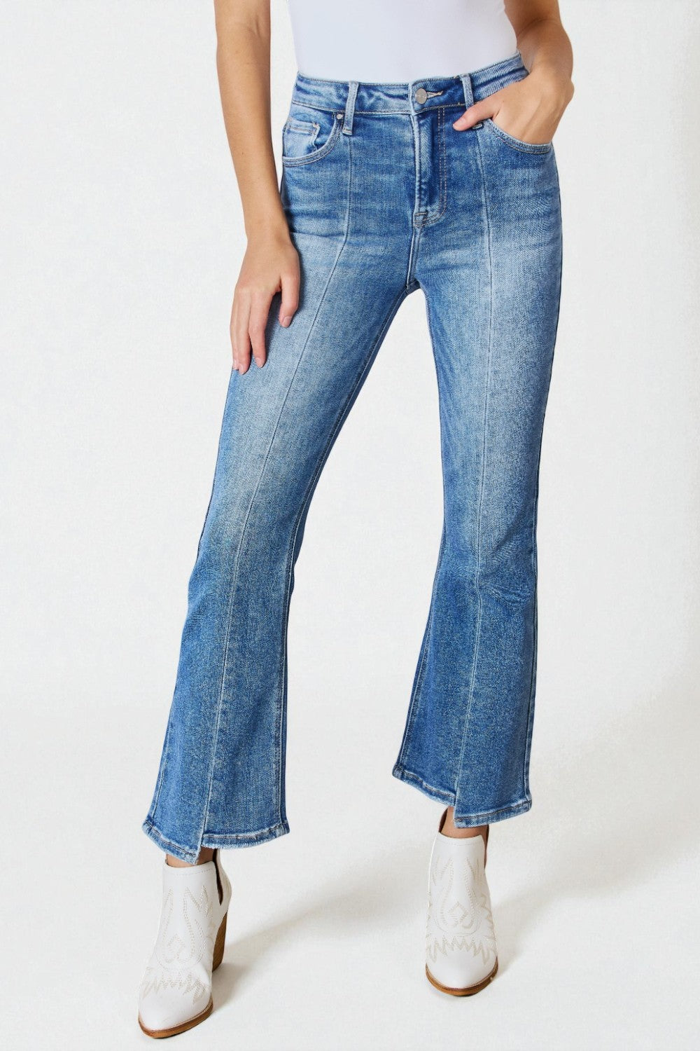 Person wearing blue jeans and white boots on a plain background