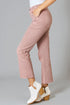 Person wearing pink jeans and white ankle boots on a gray background