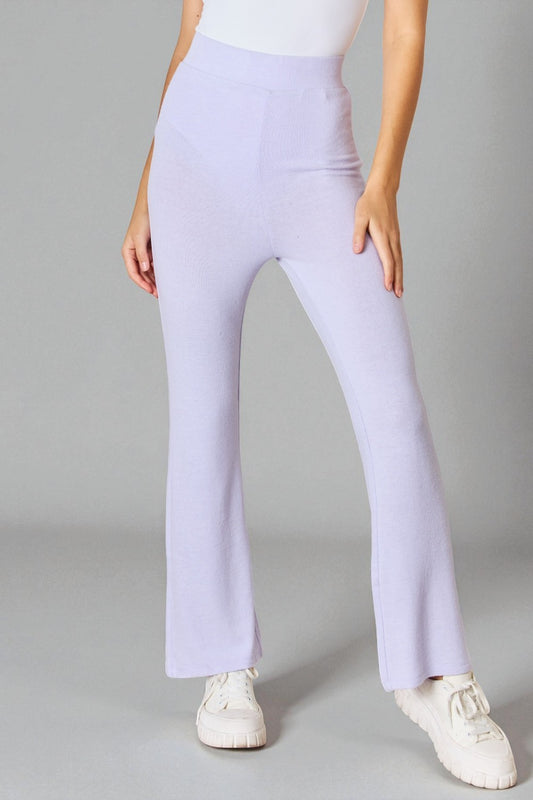 Person wearing light purple pants and white shoes on a gray background