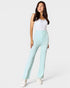Woman wearing light blue pants and a white top on a white background