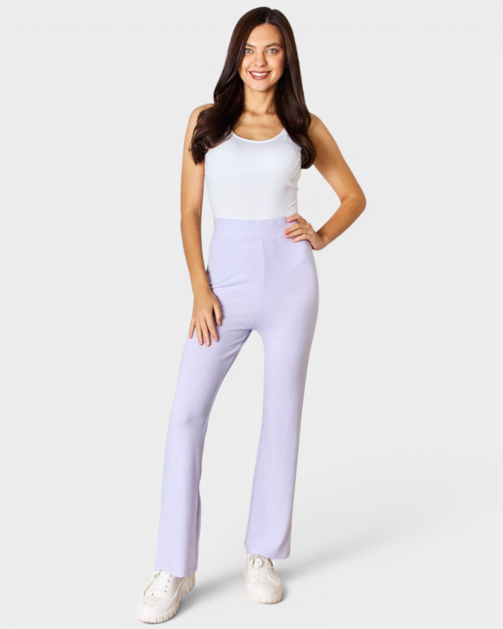 Woman wearing a white top and light purple pants on a white background