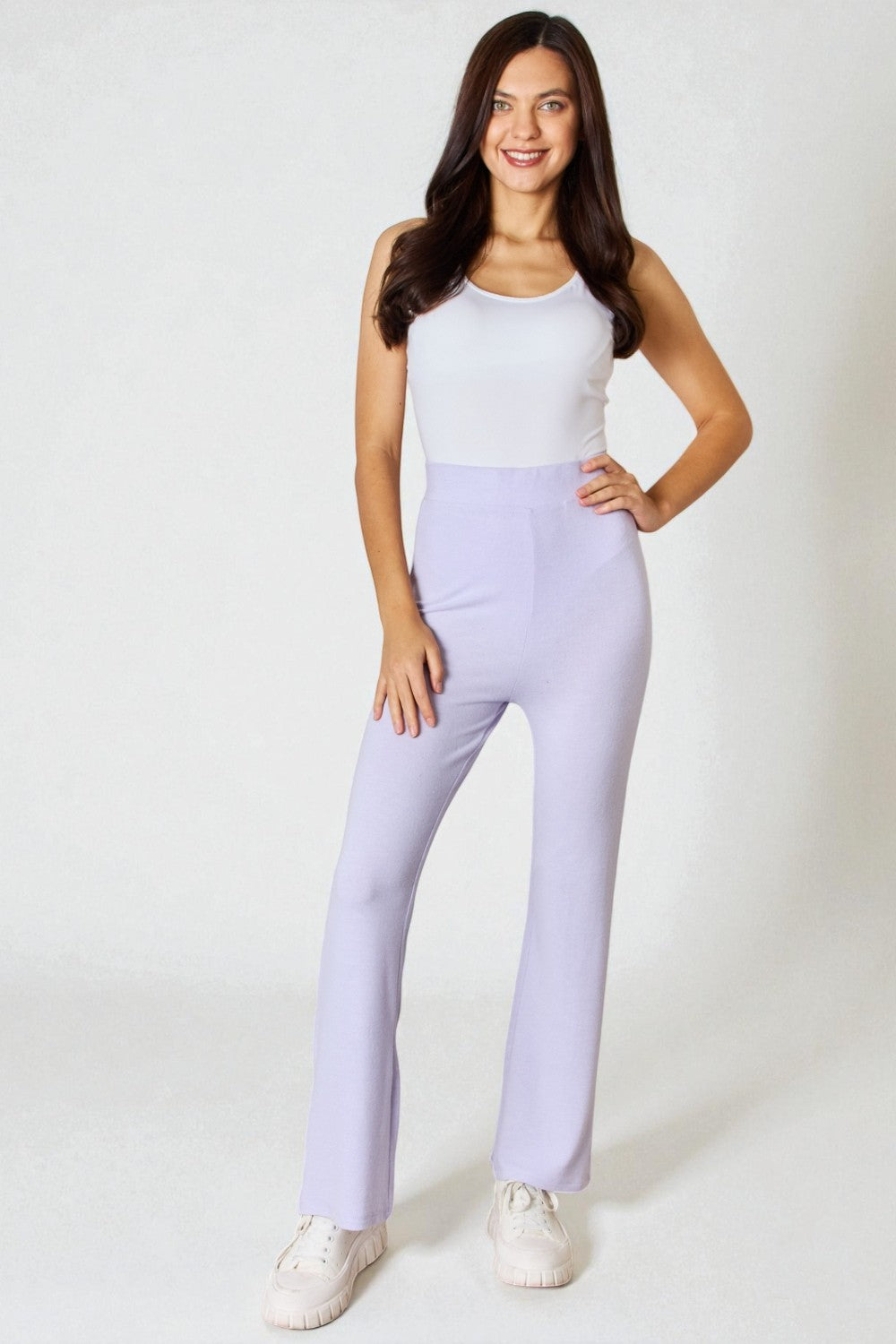 Woman wearing a white top and light purple pants on a white background