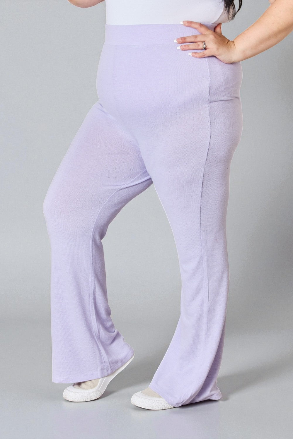 Person wearing light purple flared pants on a gray background