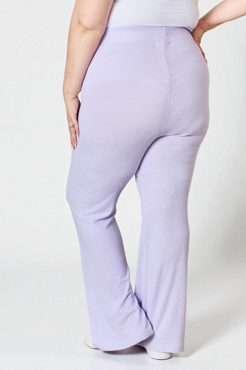 Person wearing lavender flared pants on a white background