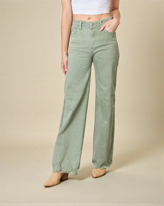 Person wearing light green wide-leg jeans on a beige background