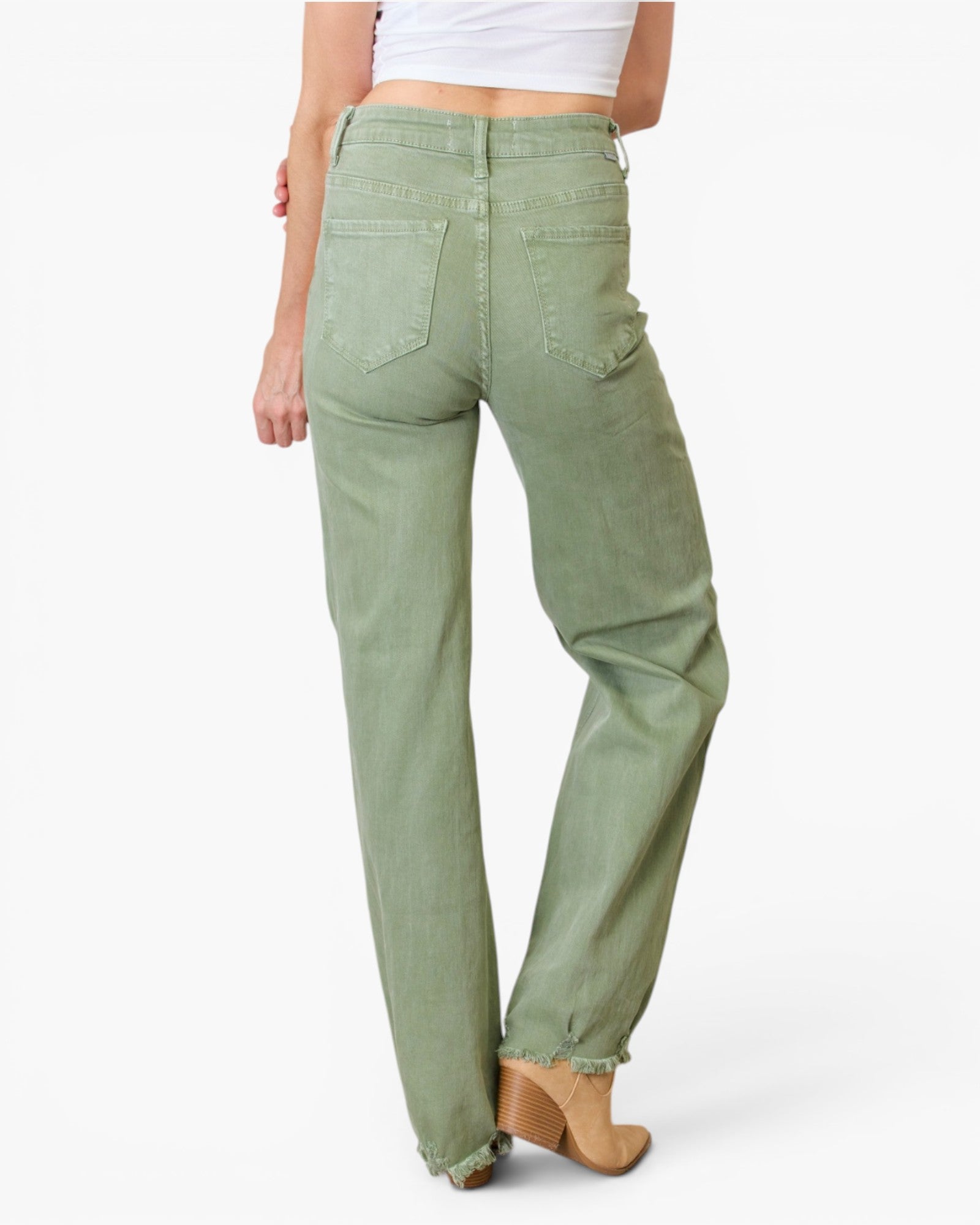 A model shown from the back wearing sage green wide-leg jeans with a frayed hem and tan heeled boots, against a plain white studio background.