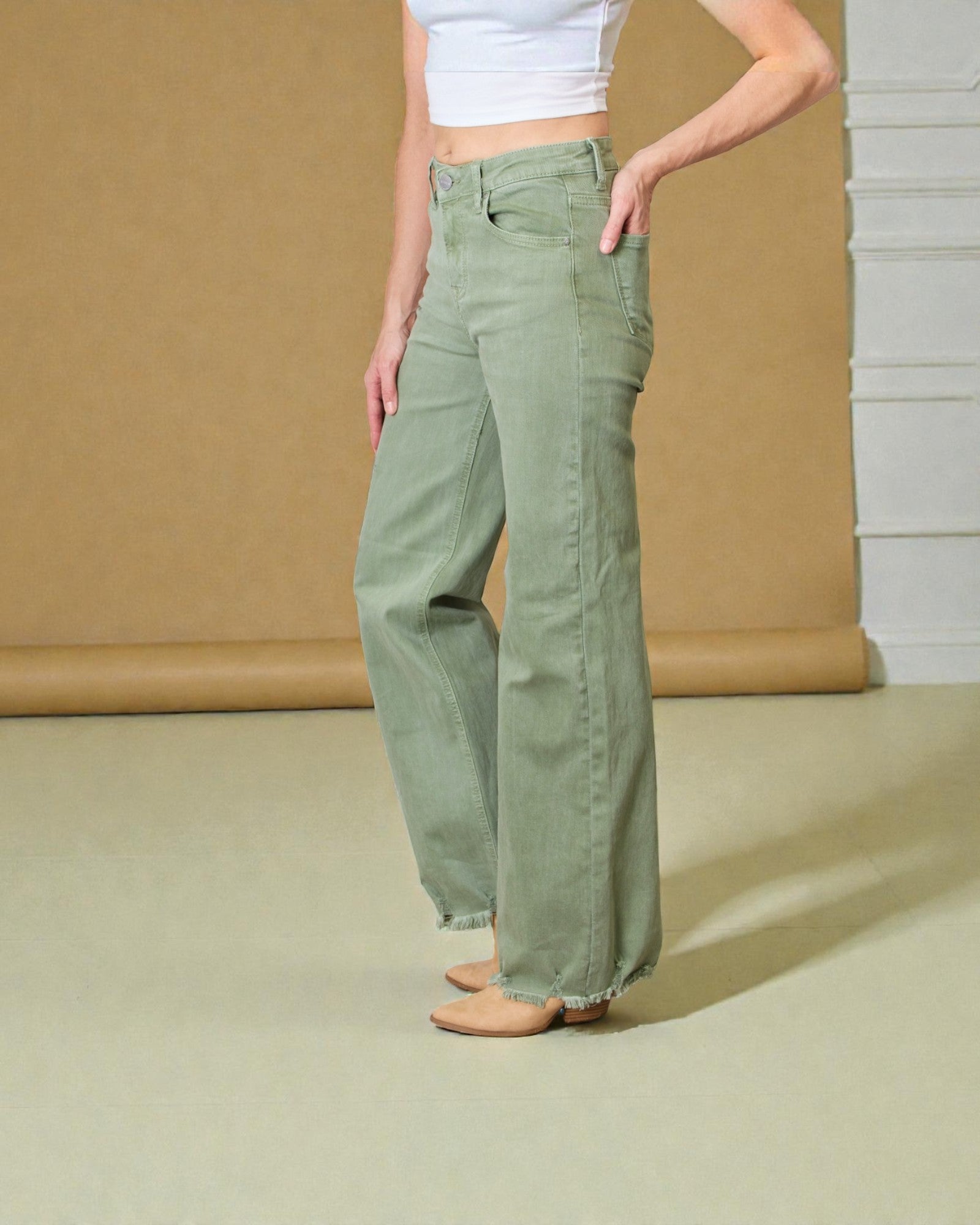 Person wearing green pants standing against a neutral background