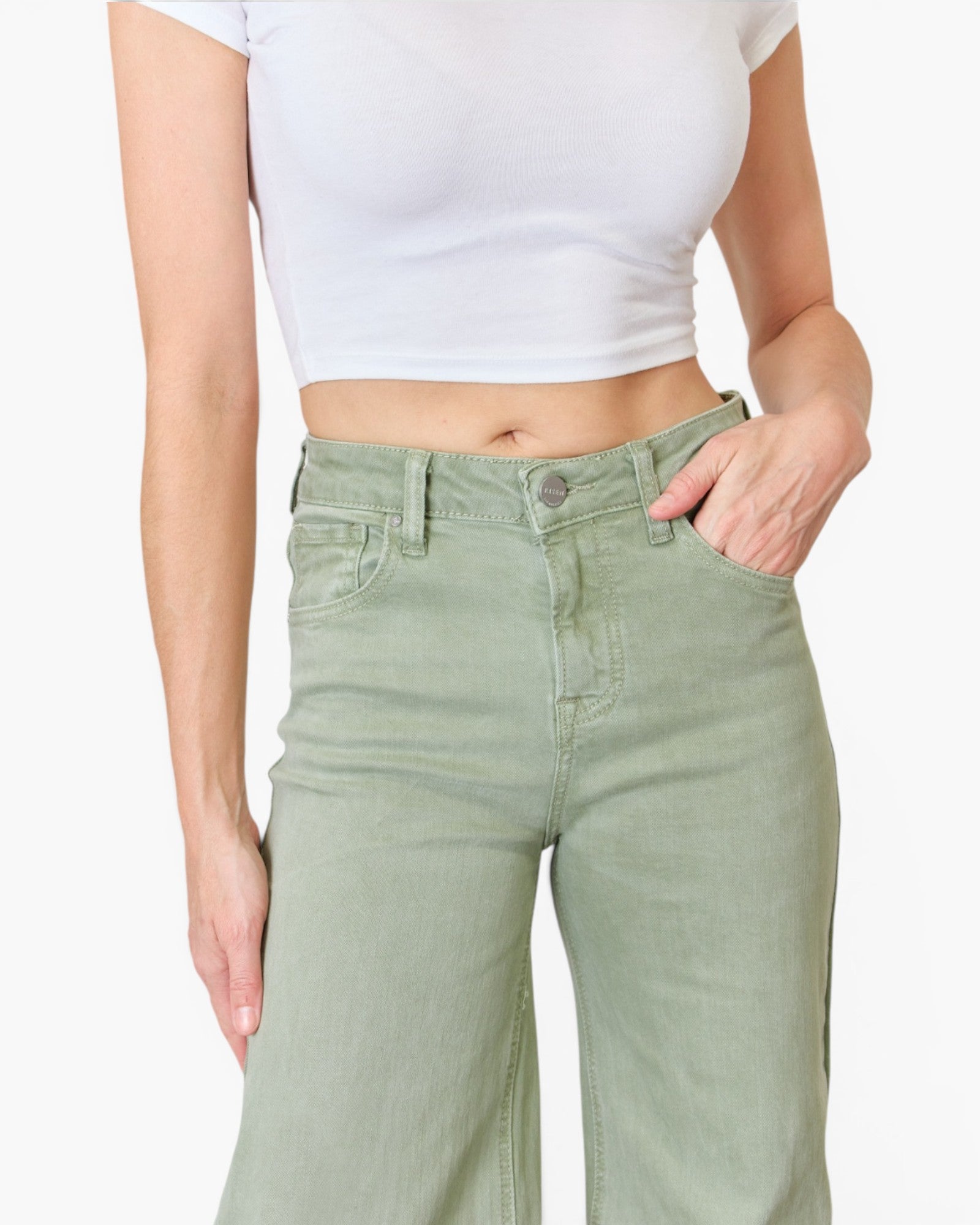 A model wearing sage green wide-leg jeans and a white crop top, cropped from the chest down against a light gray background.
