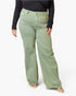 A model wearing sage green wide-leg jeans with a black long-sleeve top and beige flat sandals, shown from the waist down against a plain white background.