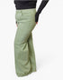 A person wearing sage green wide-leg pants and a black long-sleeve top, shown from the waist down against a plain white studio background.