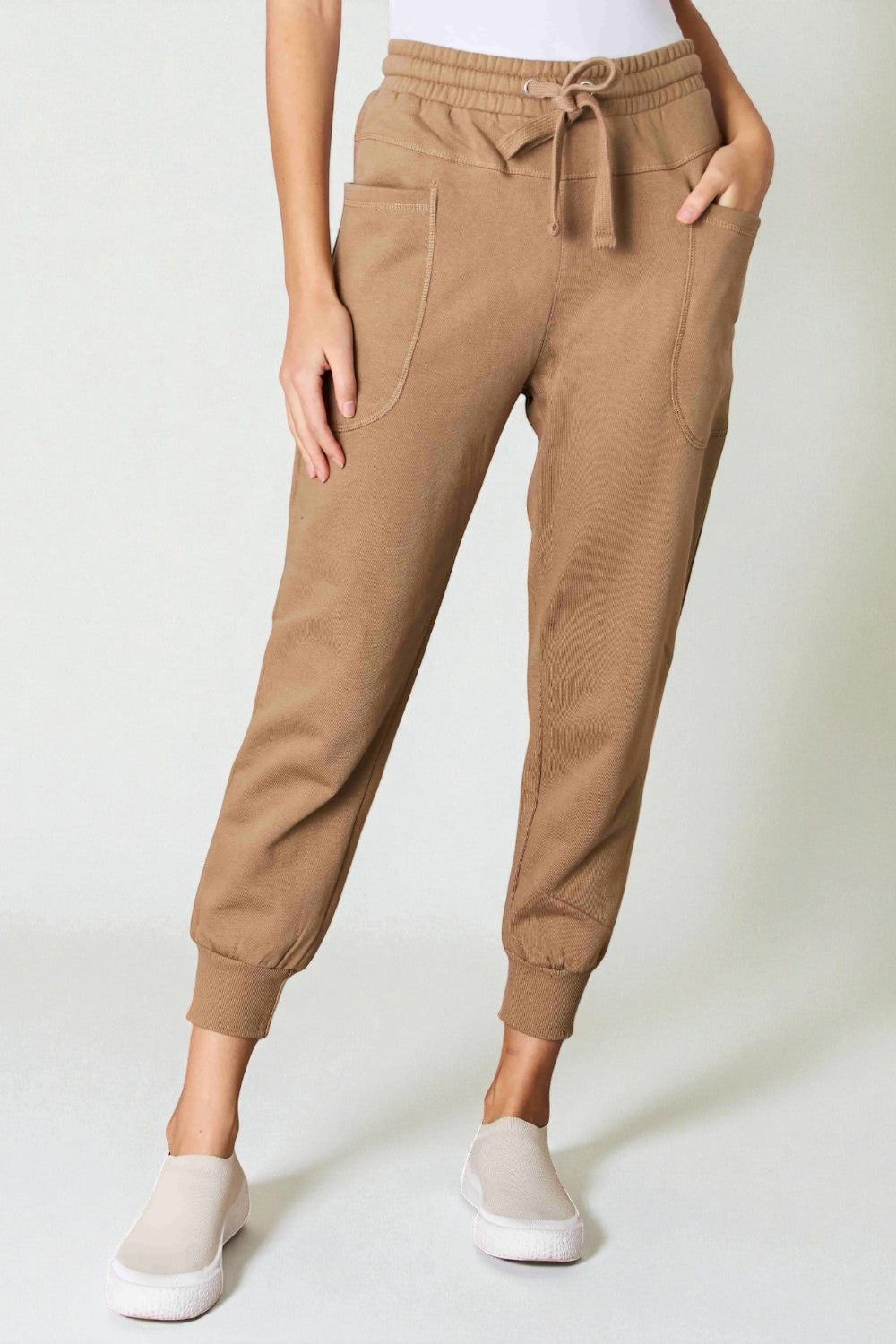 Tan jogger pants worn by a person on a white background