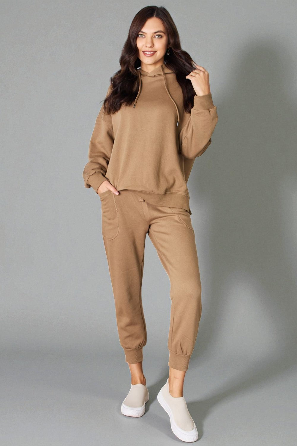 Woman wearing a beige tracksuit against a gray background