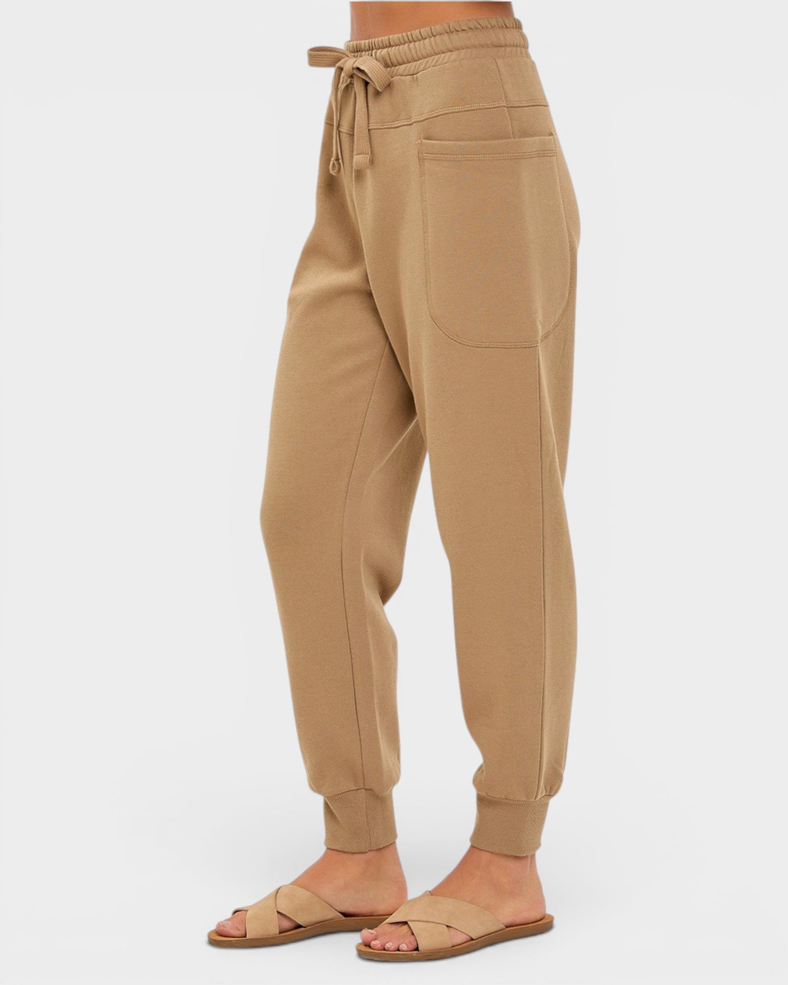 Tan jogger pants worn by a person on a white background