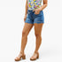 A model wearing blue denim cut-off shorts with a frayed hem, paired with a colorful floral print top and brown platform sandals, shown from the waist down on a white studio background.