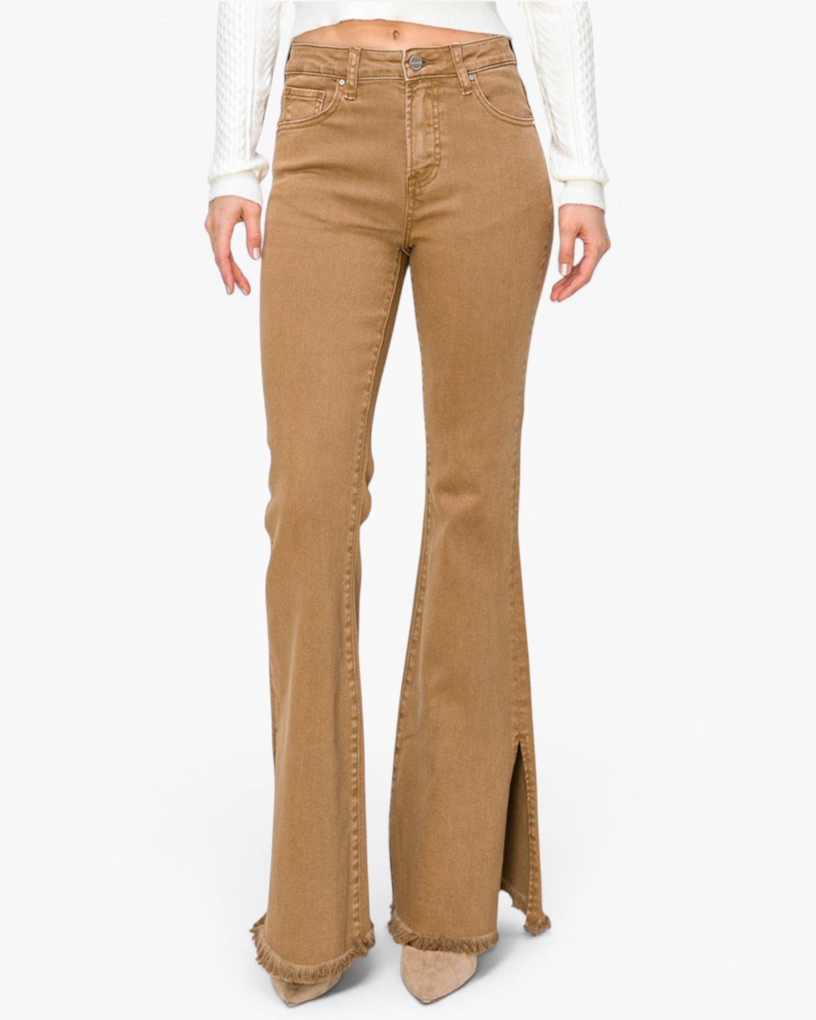 A model wearing tan flare jeans with frayed hems and side slits, paired with a white ribbed long-sleeve top and beige pointed-toe heels, shown against a plain white background.