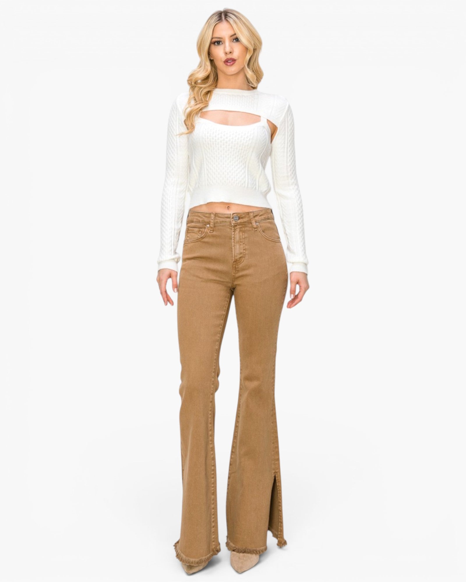 A woman modeling a white long-sleeve knit top with a chest cutout and tan flared jeans against a plain white studio background.