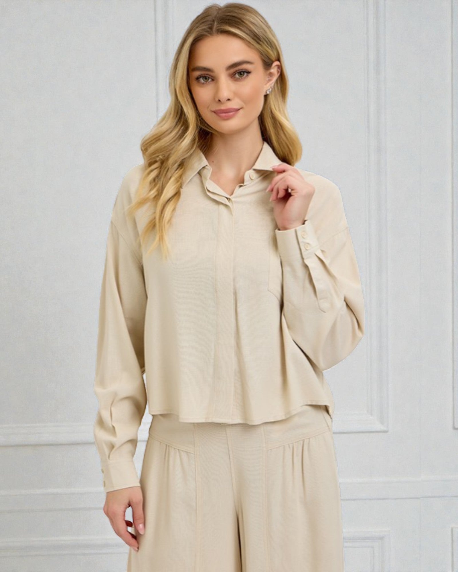 Woman wearing a beige outfit against a white wall