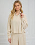Woman wearing a beige outfit against a white wall