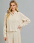 Woman wearing a beige blouse and pants against a gray background