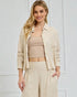 Woman wearing a beige outfit with a matching jacket against a white background