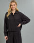 Woman wearing a black outfit against a gray background