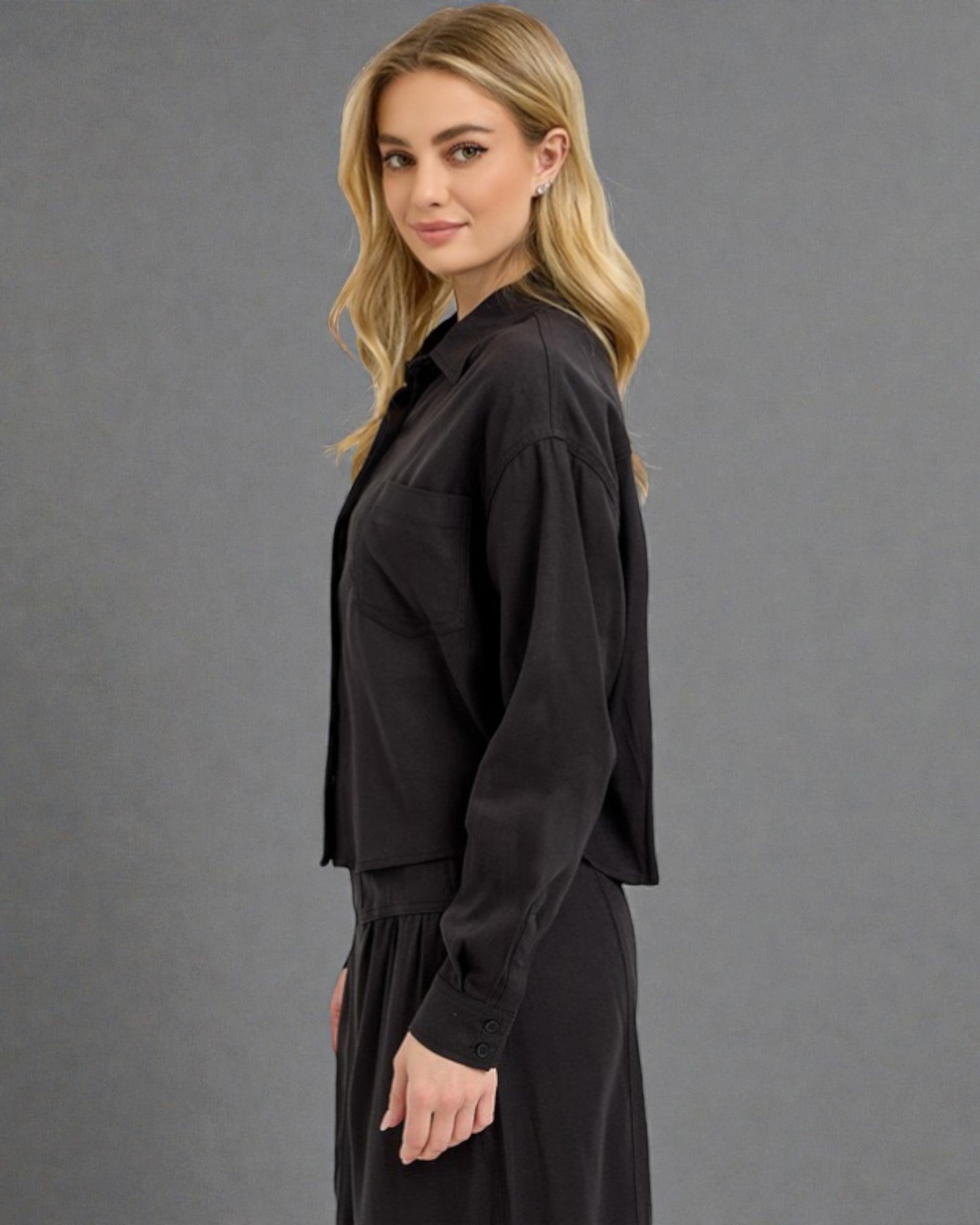 Woman wearing a black outfit against a gray background