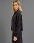 Woman wearing a black outfit against a gray background