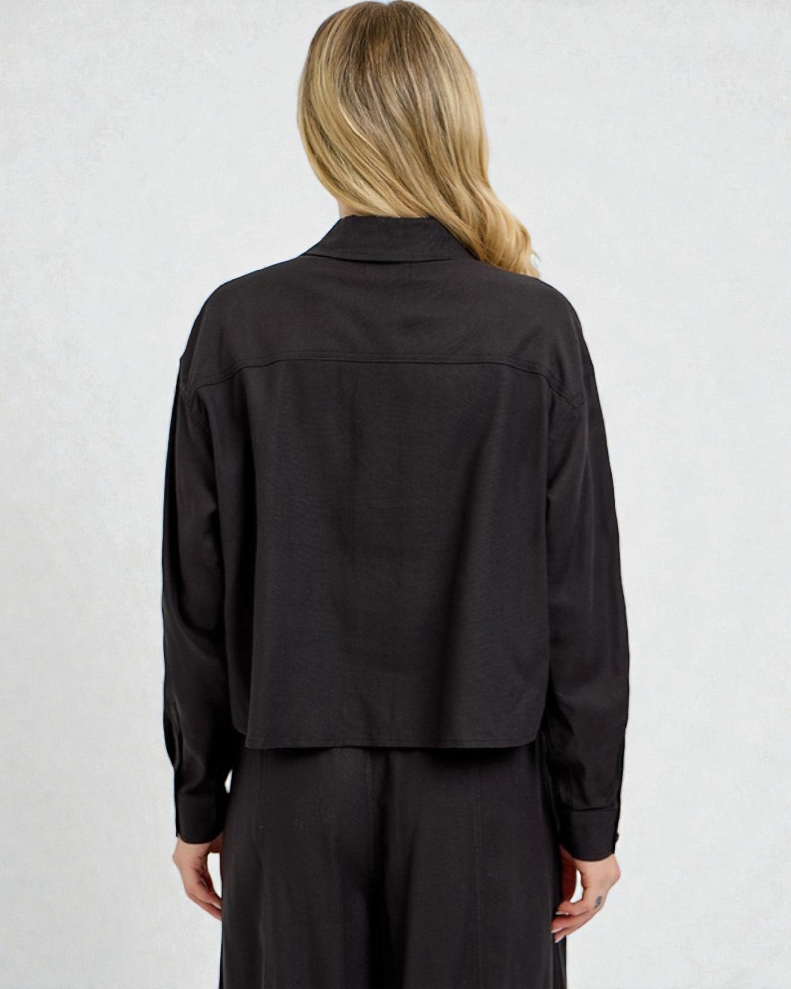 Person wearing a black long-sleeve shirt against a white background
