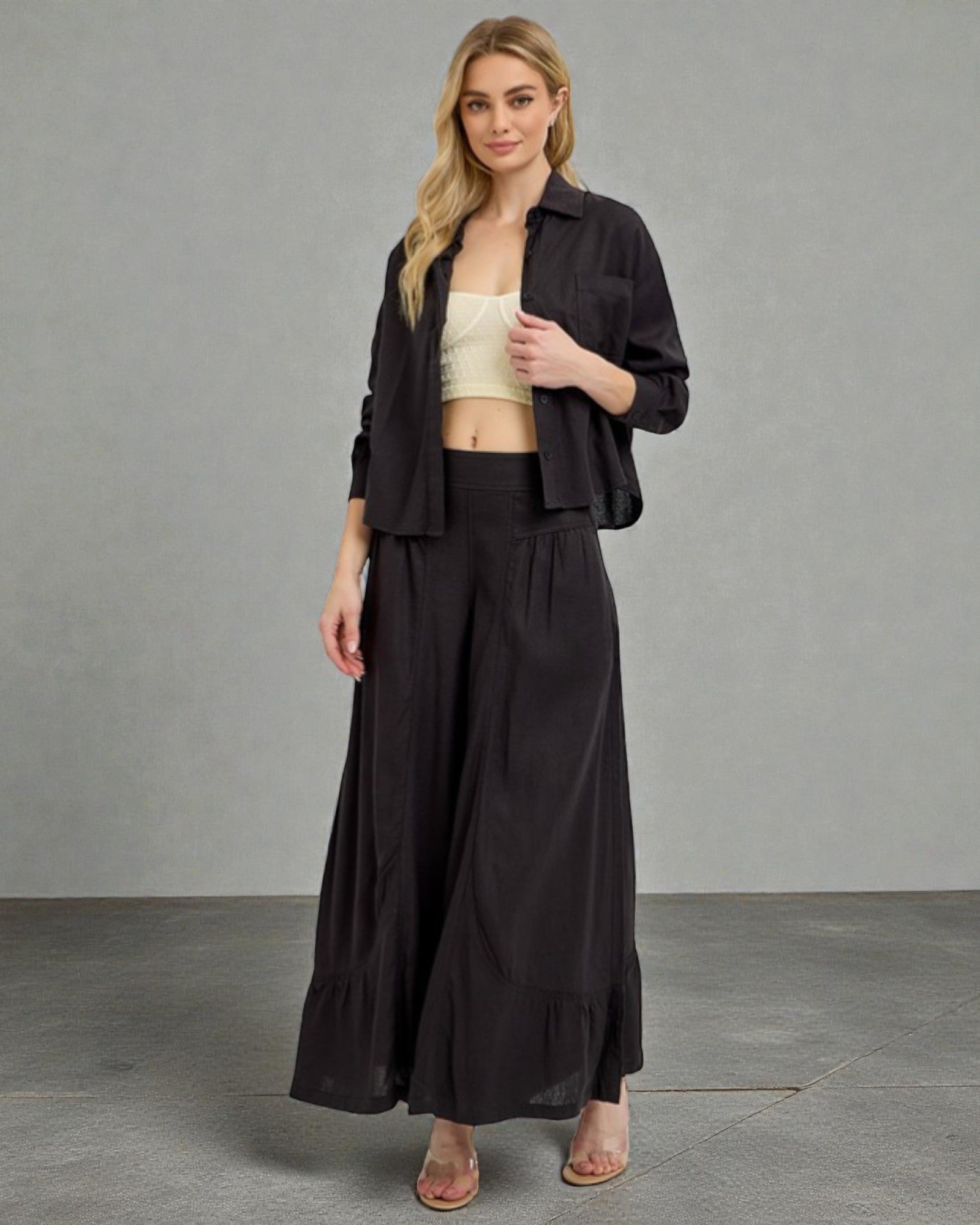 Woman wearing a black outfit with a beige top against a gray background