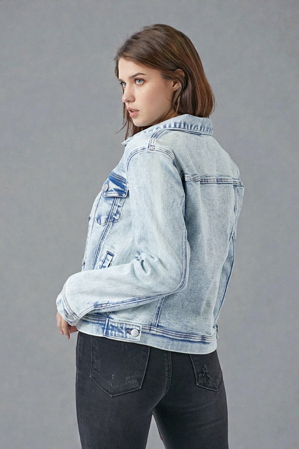 Woman wearing a light blue denim jacket on a gray background