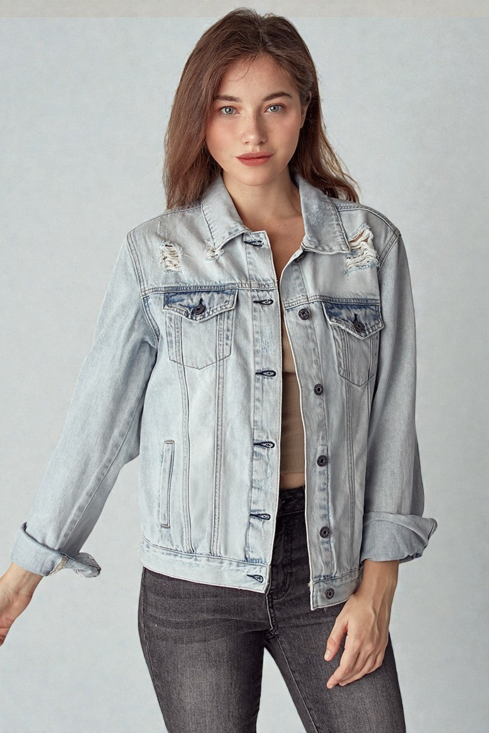 Woman wearing a light blue denim jacket on a plain background