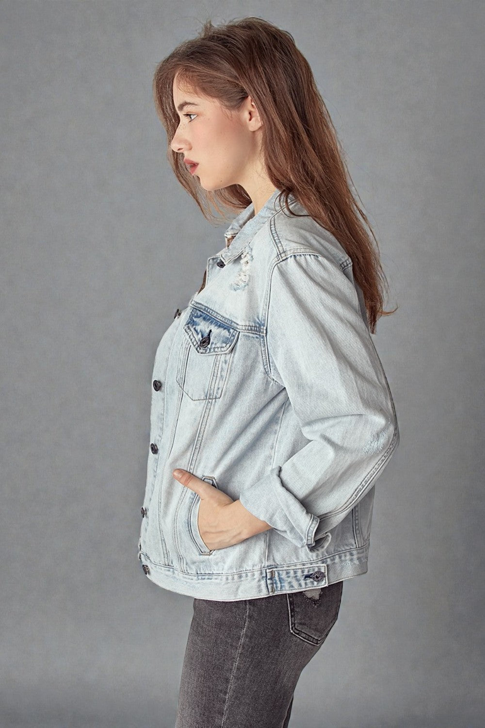 Woman wearing a light blue denim jacket against a gray background
