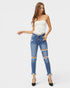 Woman wearing a white strapless top and blue ripped jeans on a white background
