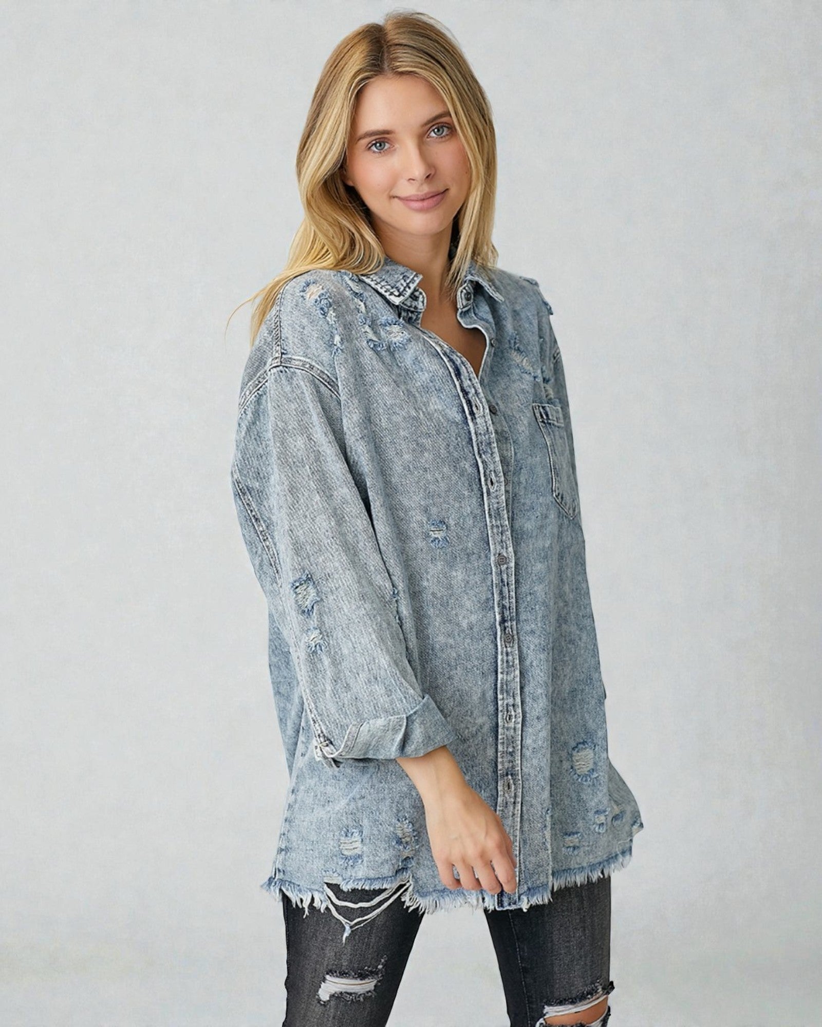 Woman wearing a distressed denim shirt against a plain background