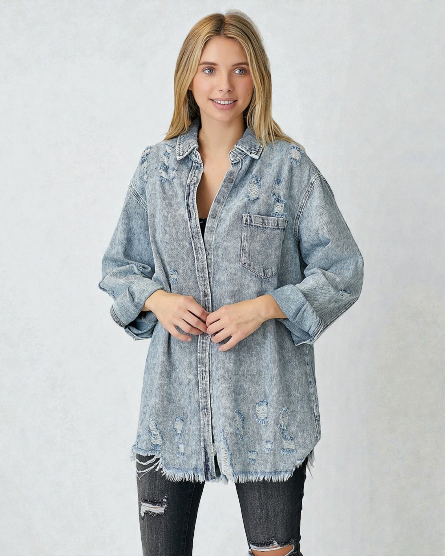 Woman wearing a light blue distressed denim jacket on a white background
