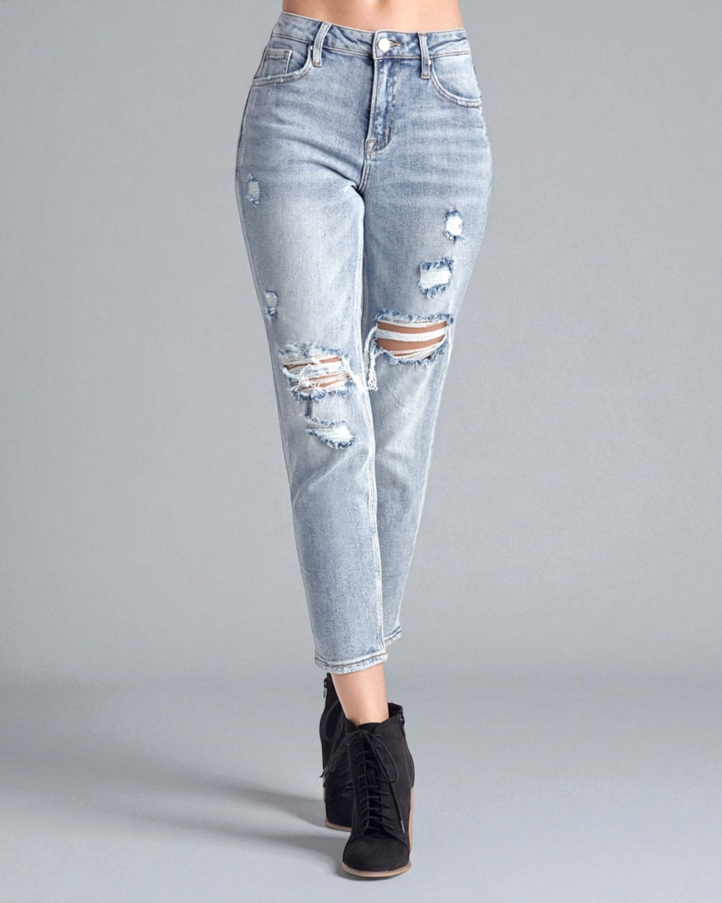 Light blue distressed jeans worn by a person on a gray background