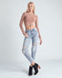 Woman wearing a brown crop top and light blue ripped jeans on a white background
