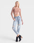 Woman wearing ripped jeans and a sheer top on a white background